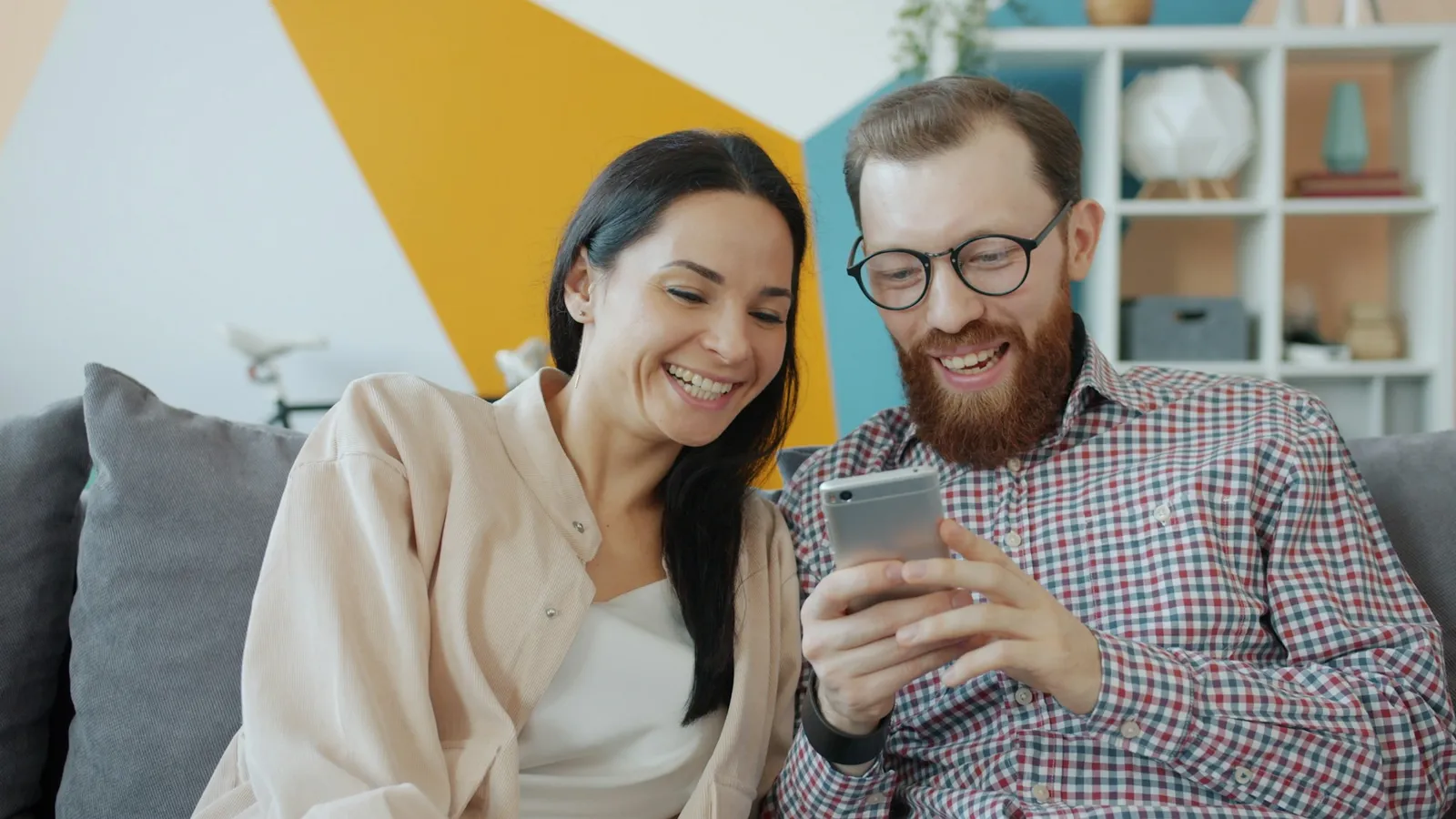 Smiling couple on a couch looking at a phone together