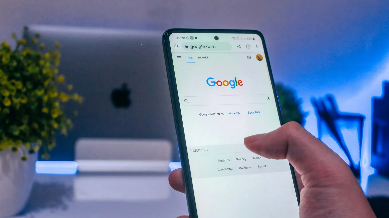 Hand holding a smartphone with the Google search page open