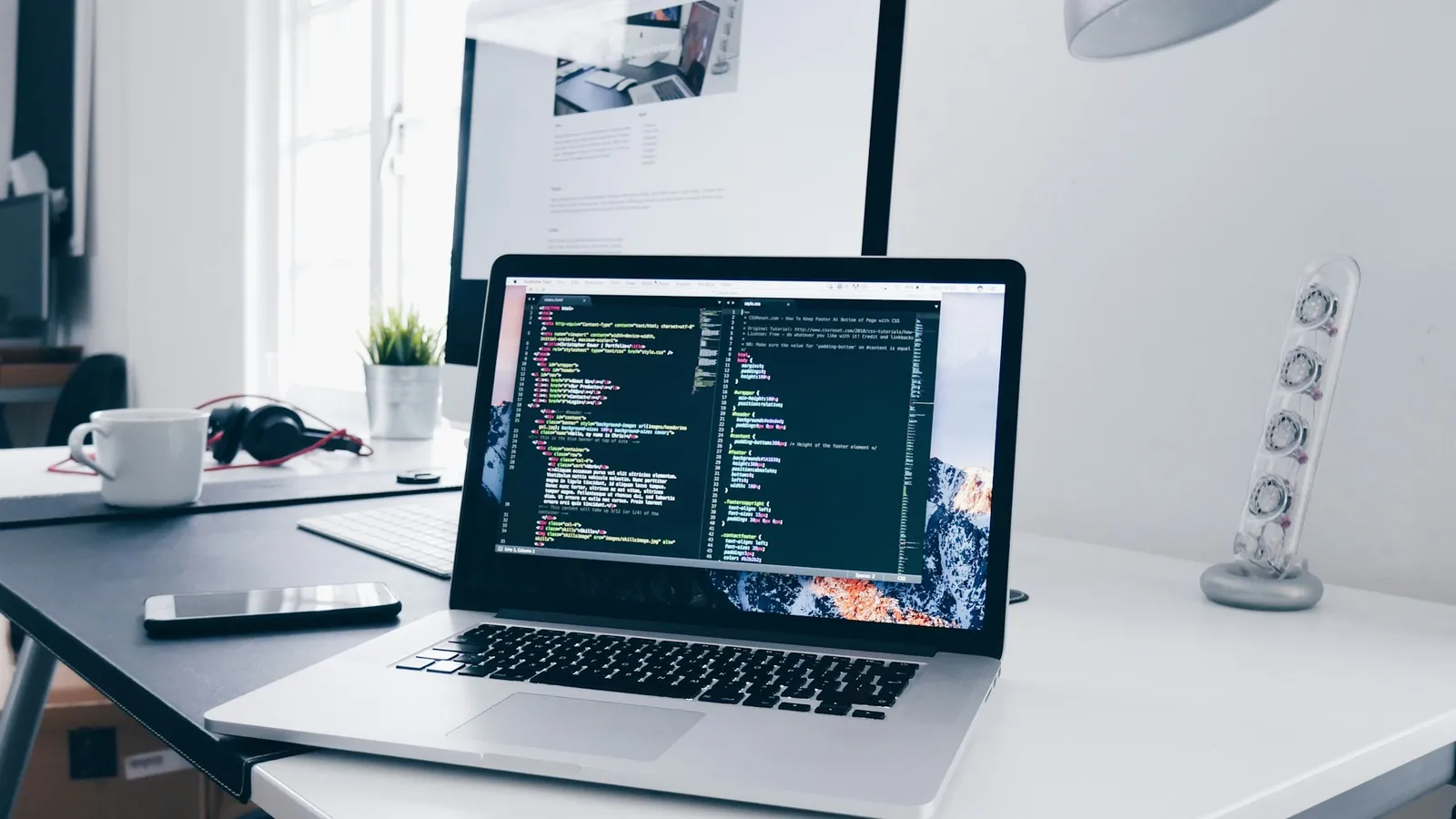 Laptop showing code on a busy desk