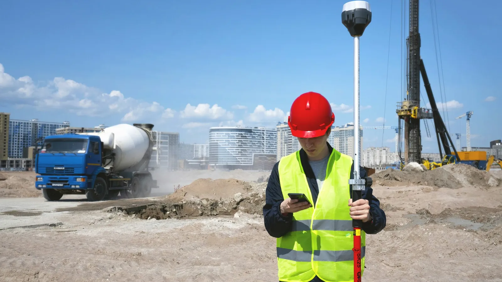 Contractor in a hard hat and safety vest checking his phone on a job site
