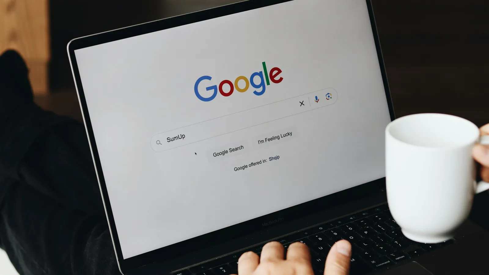 Person typing a search into Google on a laptop